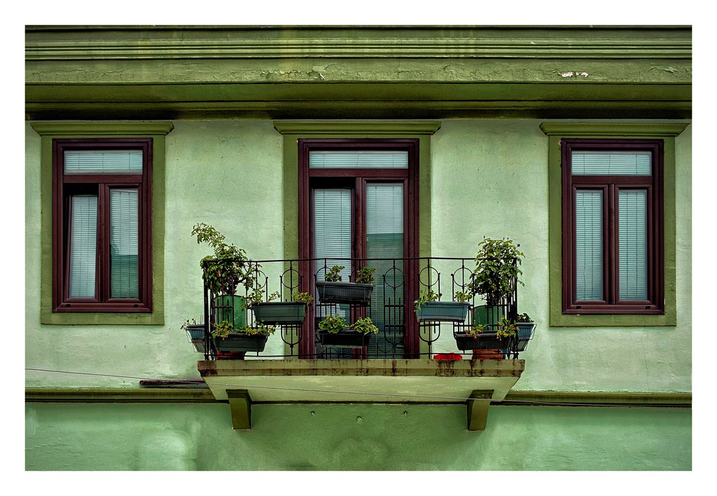 Small balcony with railing planters on a green building facade