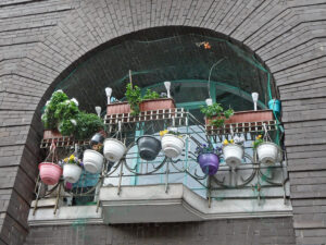 Balcony railing filled with hanging pots and rectangular planters