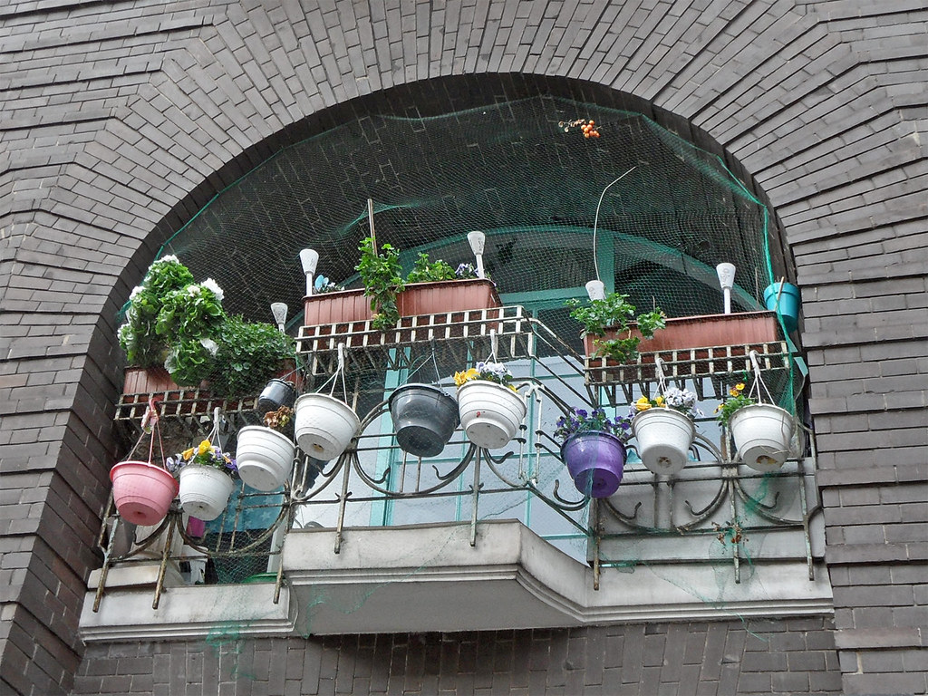 Balcony railing filled with hanging pots and rectangular planters