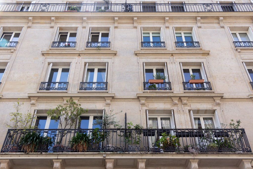 Apartment balconies with potted plants on railings and window ledges