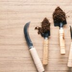 Small gardening hand tools with soil on a wooden table