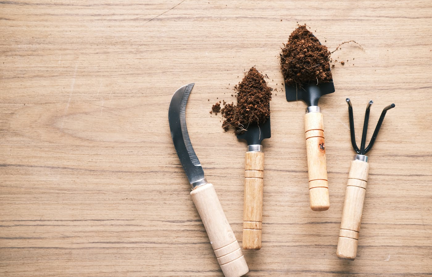 Small gardening hand tools with soil on a wooden table
