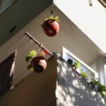 Red hanging plant pots on apartment balcony
