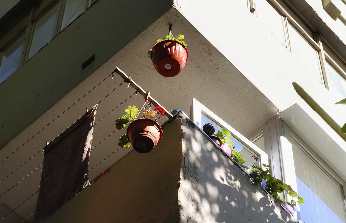 Red hanging plant pots on apartment balcony