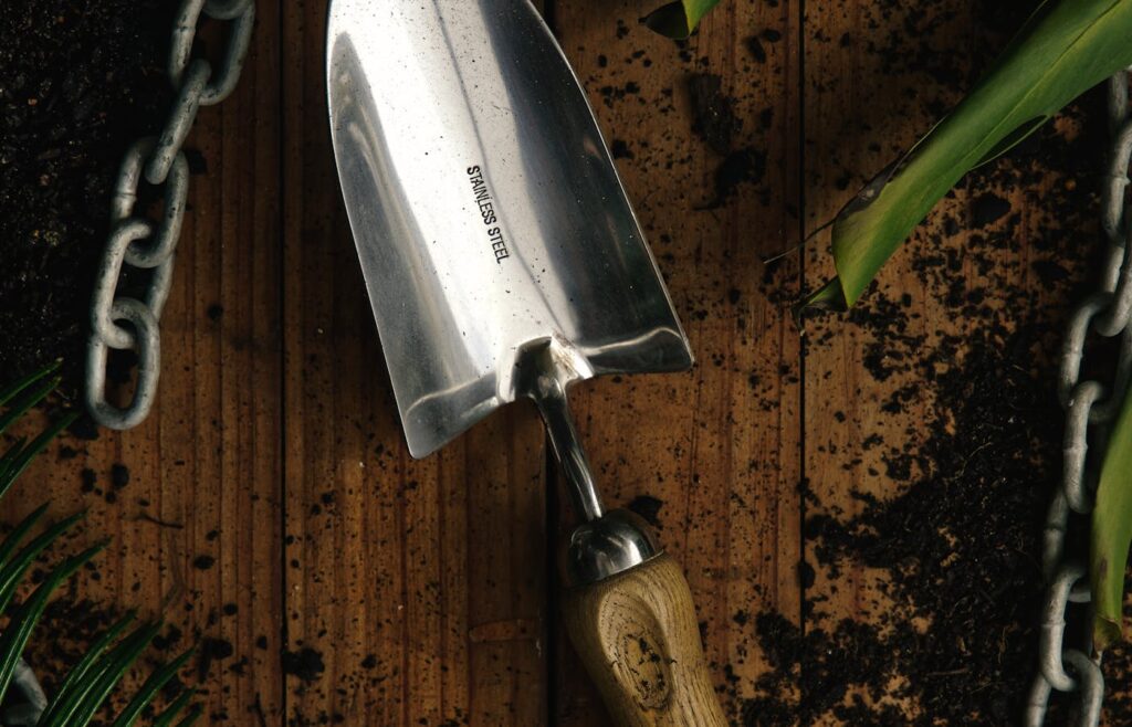 Steel garden trowel on a wooden potting bench with soil