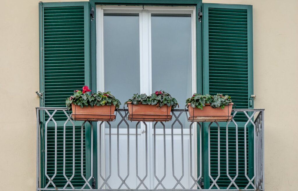 Three flower boxes attached to a balcony railing