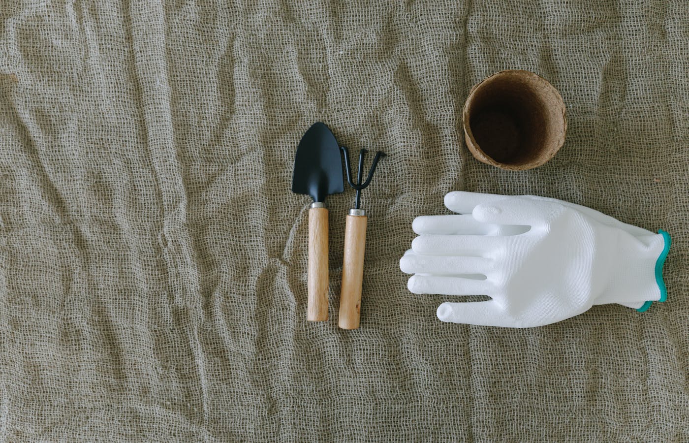 Gardening glove small trowel hand rake and seed pot on burlap